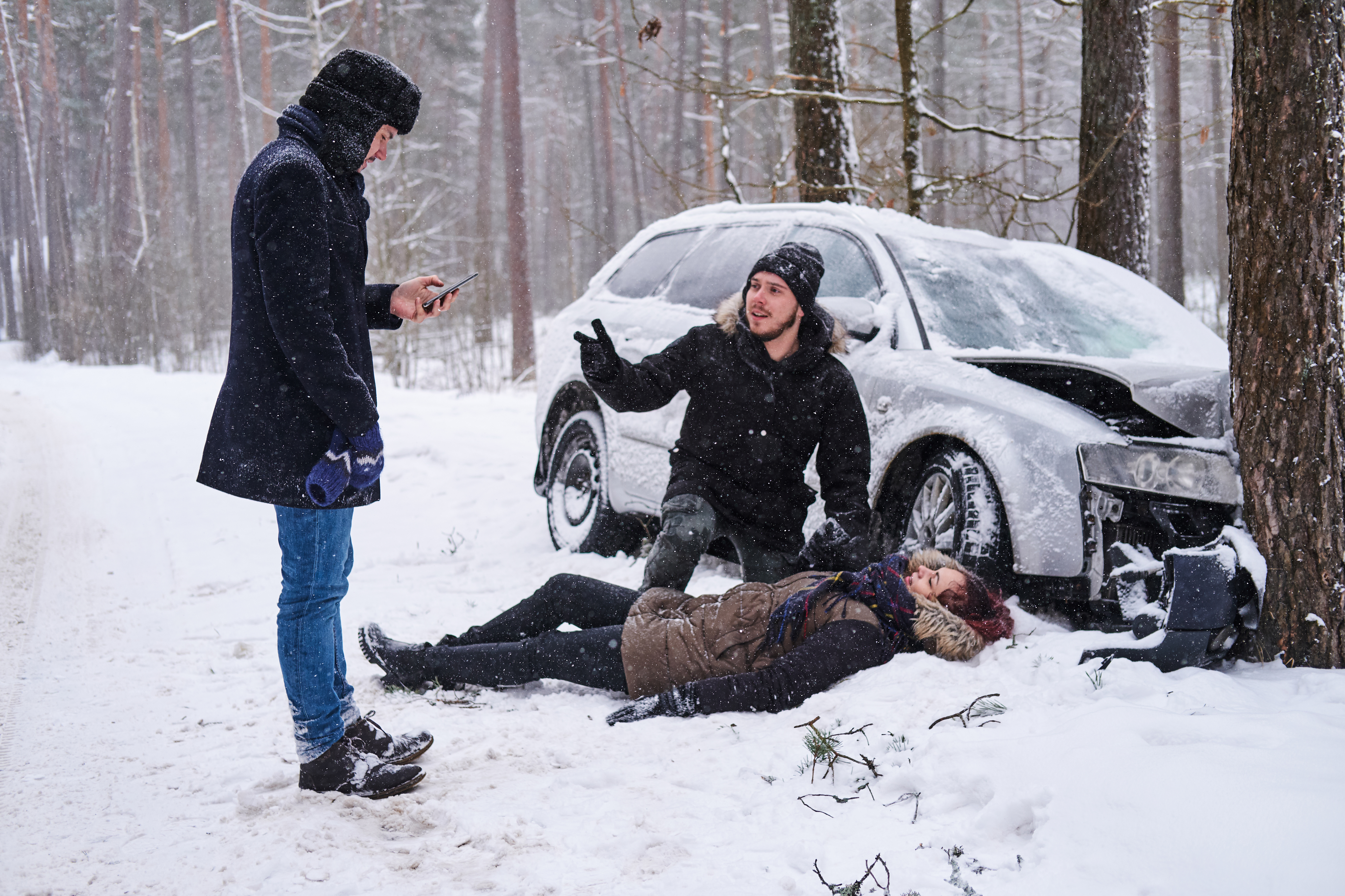 injured-woman-is-lying-snow-after-car-crush-man-is-trying-help-her-second-man-is-calling-ambulance